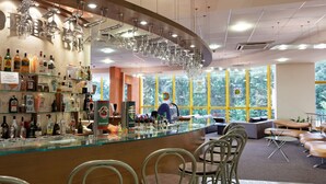 Eine Bar mit einer gebogenen Theke, verschiedenen Sitzgelegenheiten und Blick ins Freie durch große Fenster.