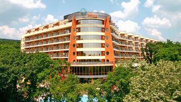 A multi-story hotel with a distinctive orange and beige facade, featuring balconies and large windows.