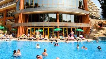 Relax by the pool surrounded by lounge chairs and umbrellas, with stunning views from the building's large windows and balconies.