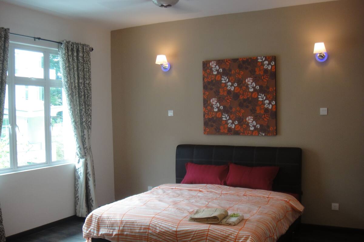 A hotel room with a bed, curtains, a window, and two wall-mounted lamps.