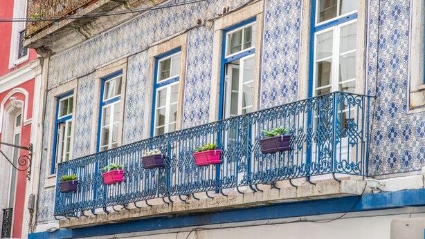 A building with blue and white patterned walls, a balcony with metal railings, and potted plants. - Inn Fashion Residence (Lisbon)