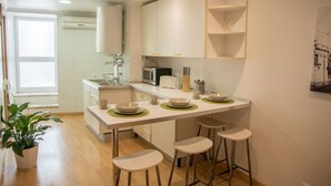 A modern kitchen with a central island, bar stools, and a microwave. - Inn Fashion Residence (Lisbon)