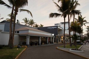 Un hotel llamado 'Casa Andina' con una fachada moderna, palmeras y un acceso pavimentado.