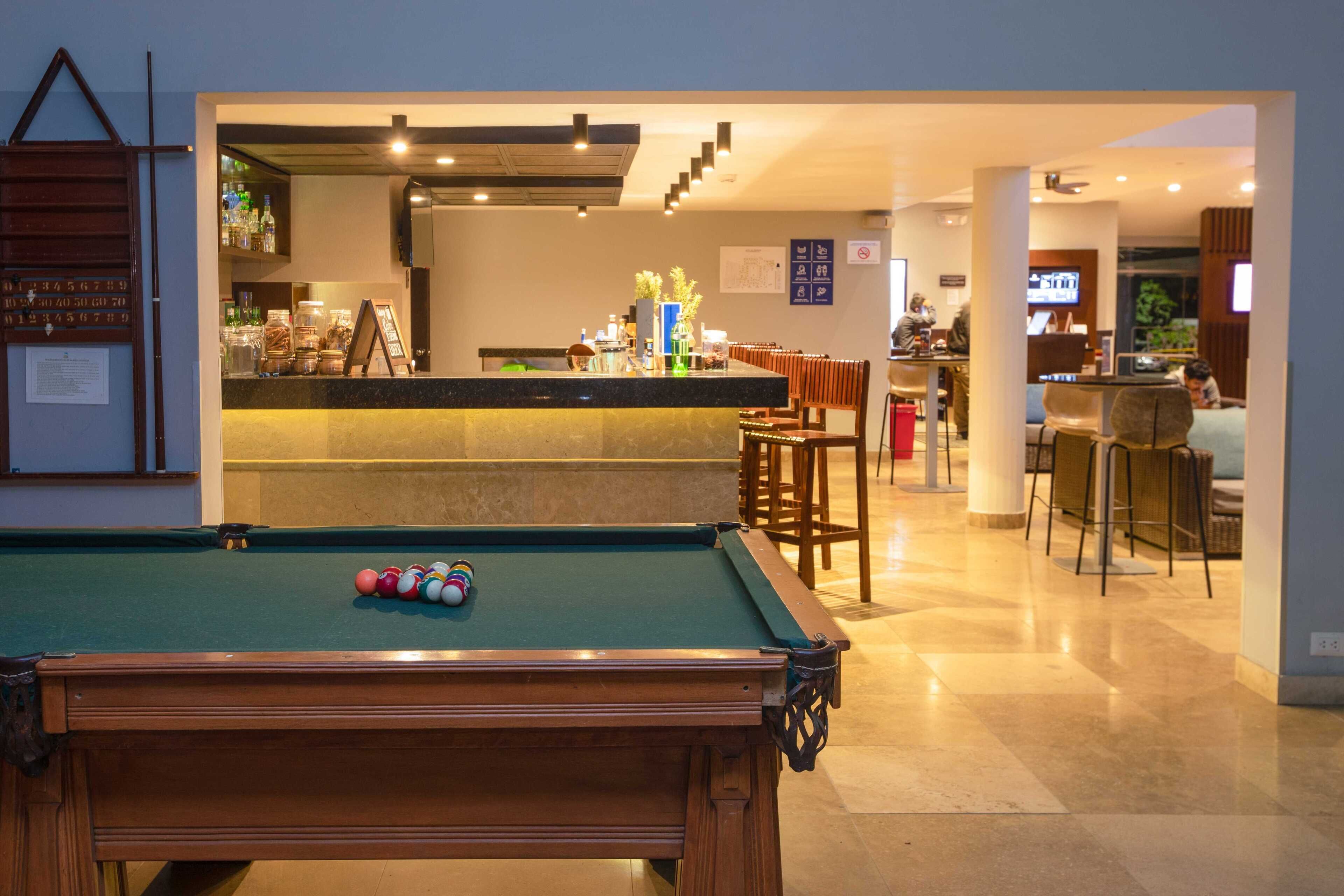A pool table with balls, a bar area with stools, and a seating area with chairs.