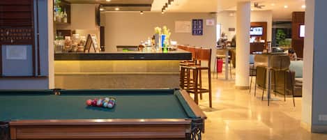 A pool table with balls, a bar area with stools, and a seating area with chairs.