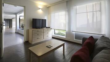 Una sala de estar moderna con un televisor de pantalla plana, una mesa de centro de madera y un sofá con cojines rojos.