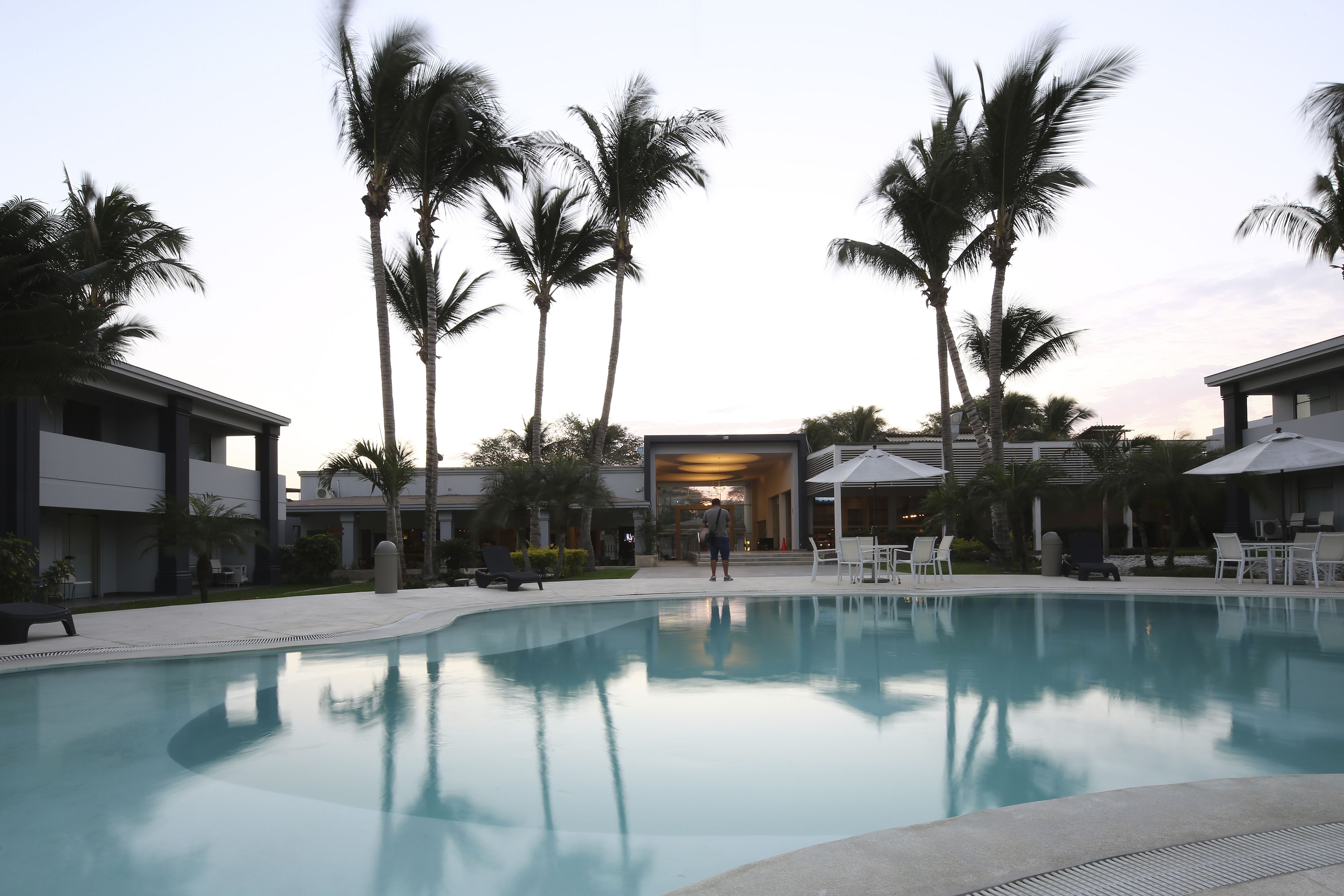 A swimming pool surrounded by palm trees and modern buildings.