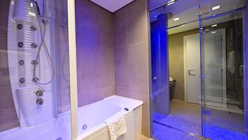 Een moderne badkamer met een douchecabine van glas, een vrijstaand bad en een glazen deur naar een ruime douche.