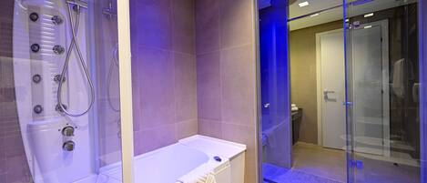 A modern bathroom with a glass-enclosed shower, a standalone bathtub, and a glass door leading to a walk-in shower.