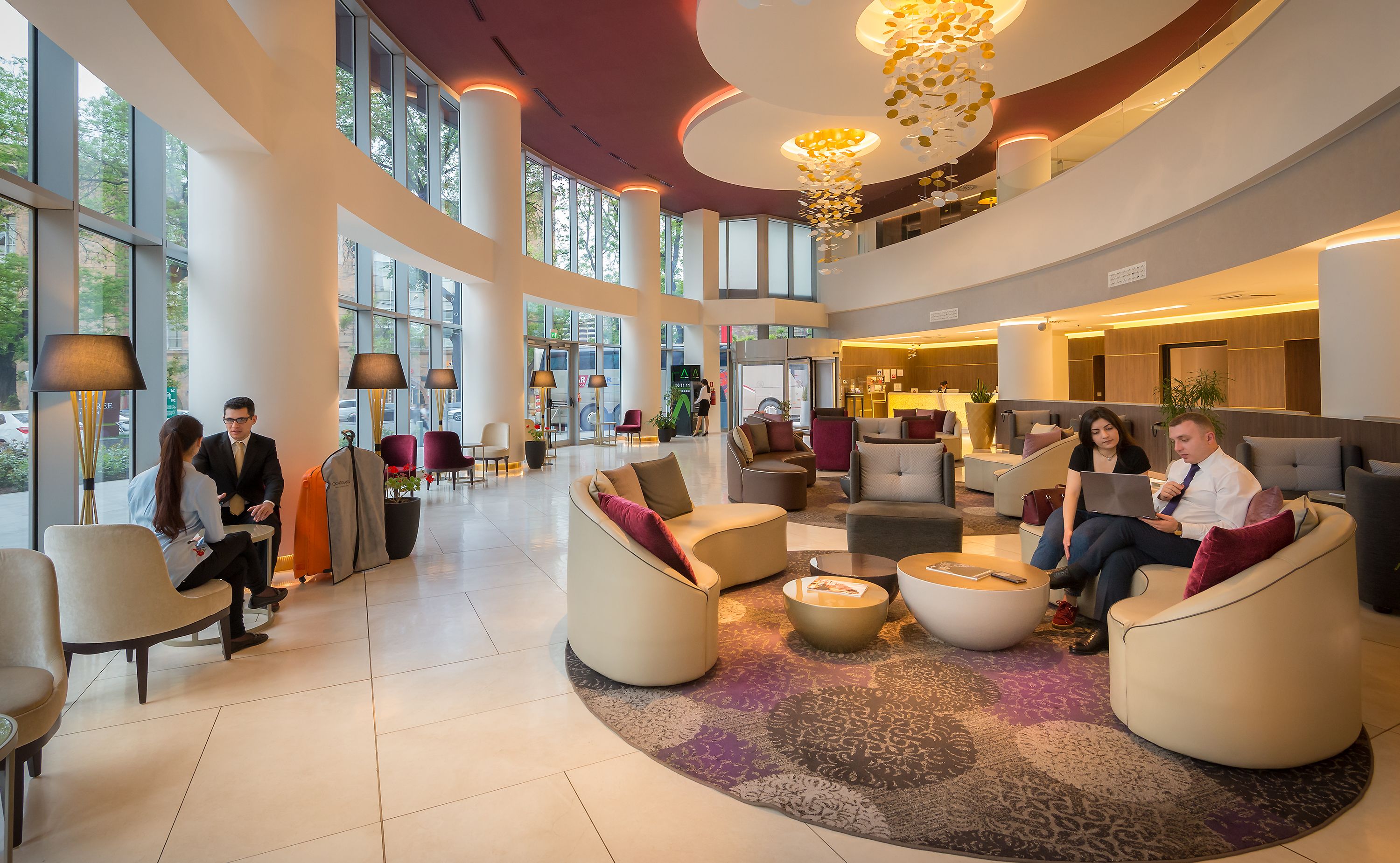 A spacious lobby with high ceilings, large windows, and modern furniture.