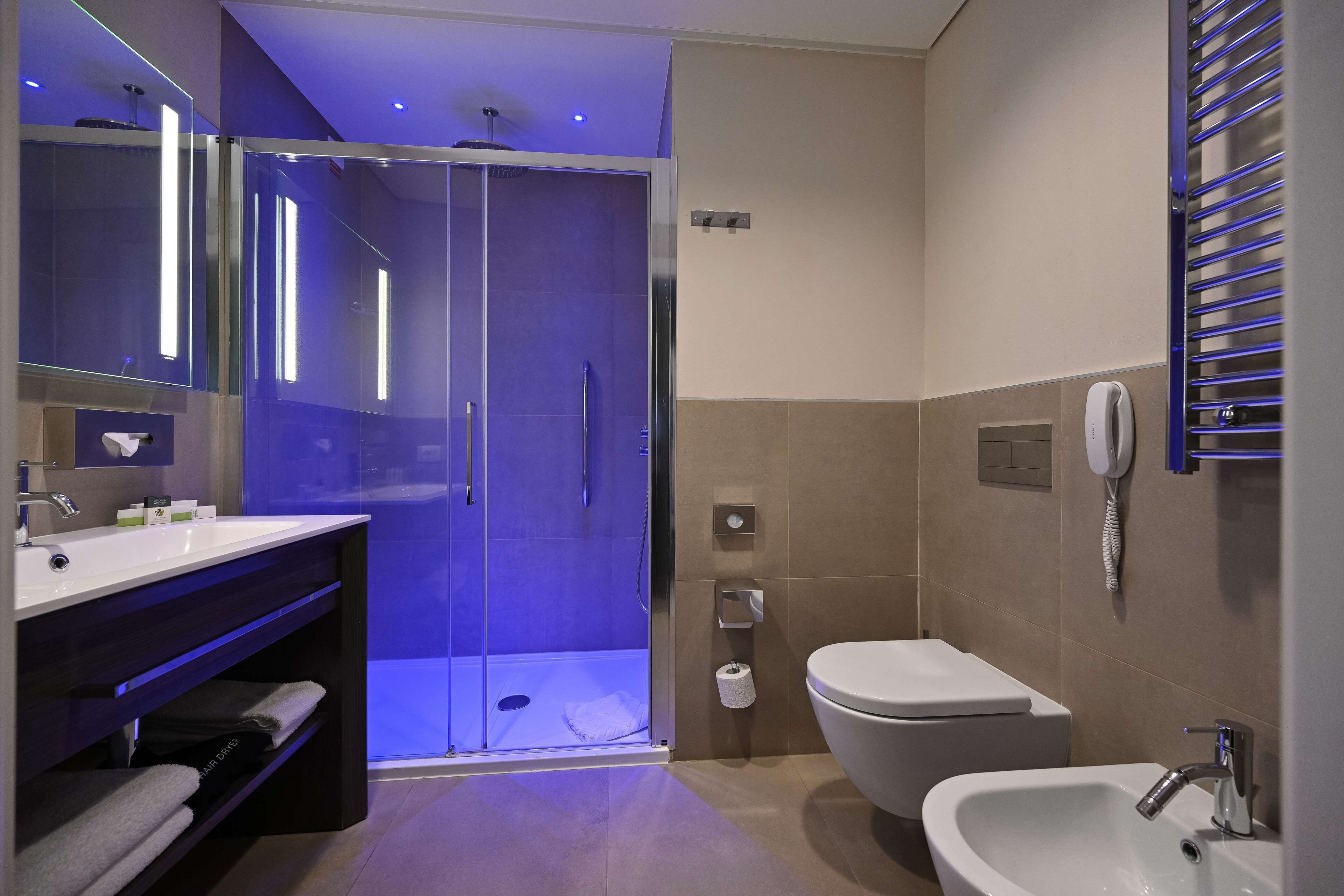 A modern bathroom with a glass-enclosed shower, a standalone sink, and a toilet.