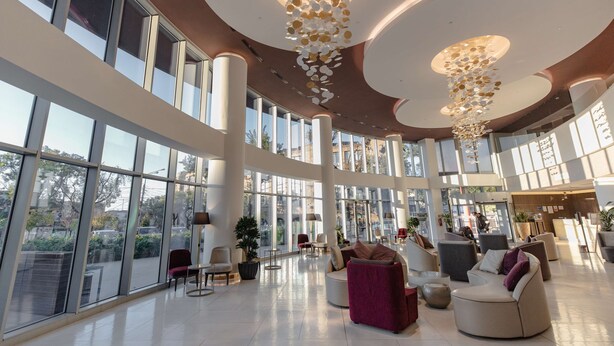Un hall d’entrée spacieux, doté de grandes fenêtres, de meubles modernes et de luminaires décoratifs au plafond.