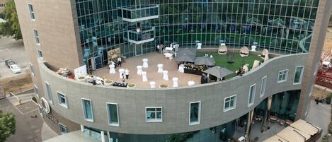 A modern hotel with a curved glass facade, outdoor seating area, and a central courtyard.