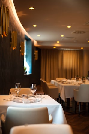 A restaurant with tables set for dining, featuring a modern interior with wooden accents and a warm ambiance.