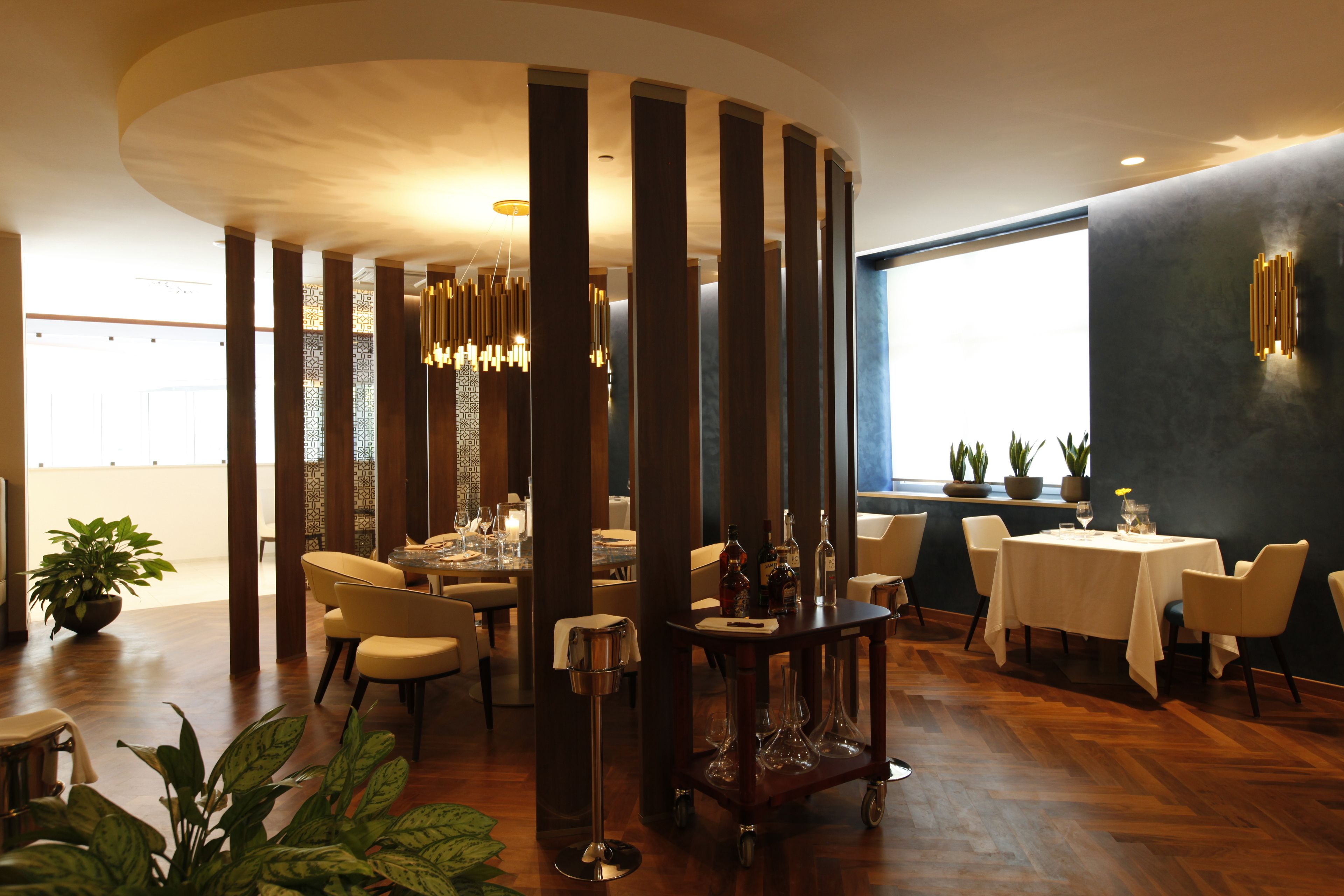 A modern dining area with high ceilings, wooden columns, and a central round table with chairs.