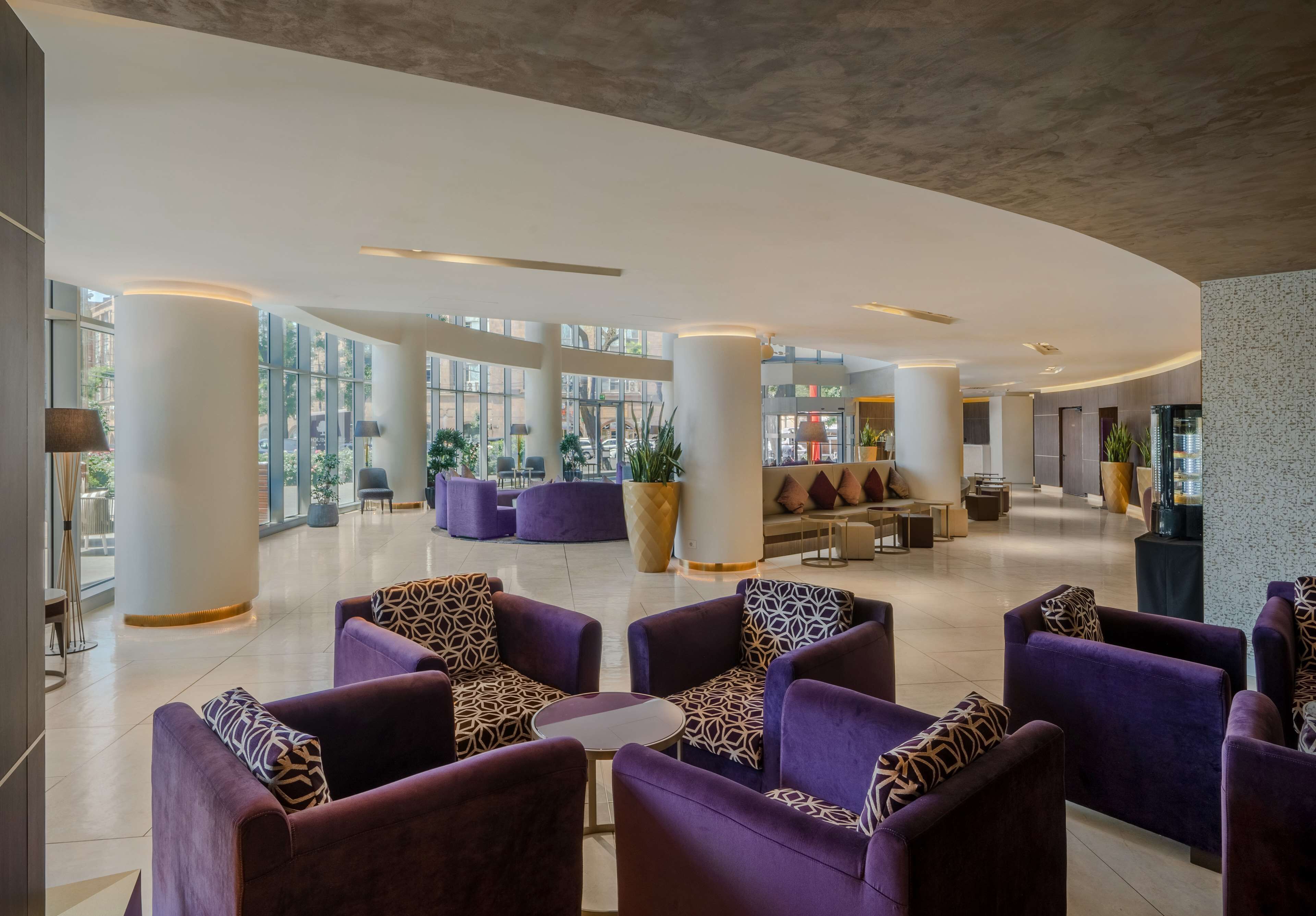 Un hall d’entrée spacieux, doté de sièges violets, de grandes fenêtres et d’un design moderne.