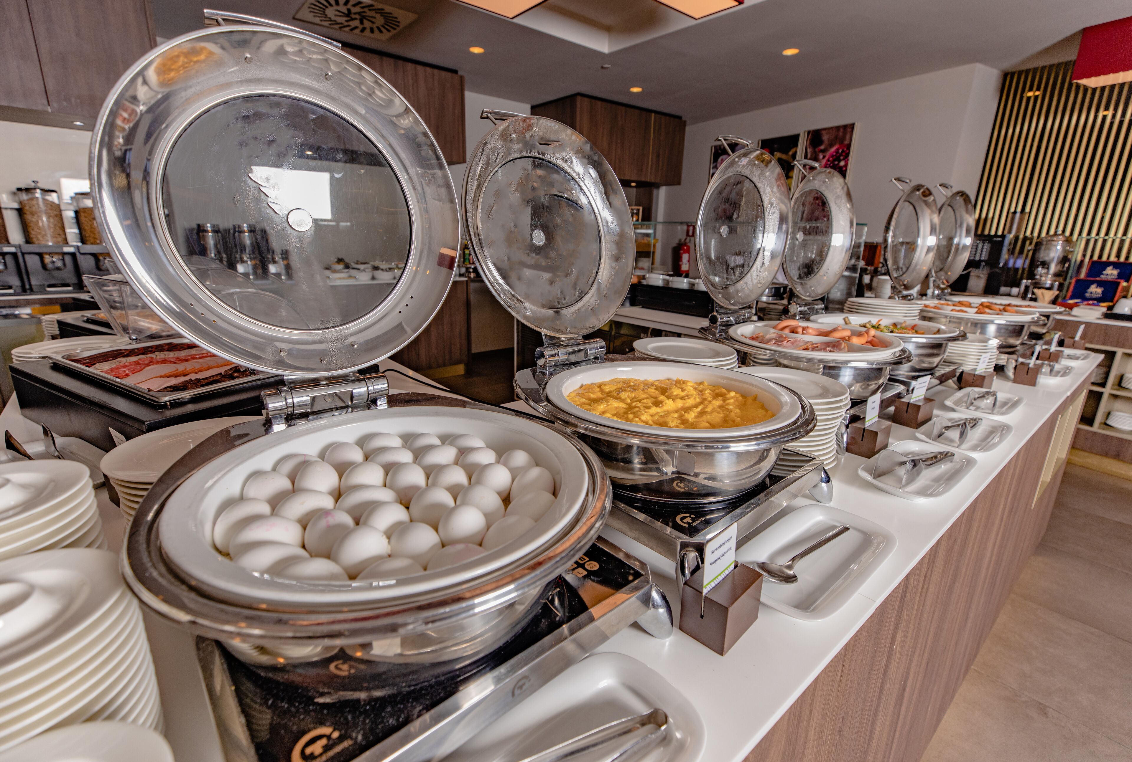 Mesa de buffet con distintos alimentos y utensilios para servir.