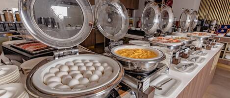 Mesa de buffet con distintos alimentos y utensilios para servir.
