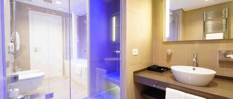 A modern bathroom with a glass-enclosed shower, a white sink, and a large mirror.