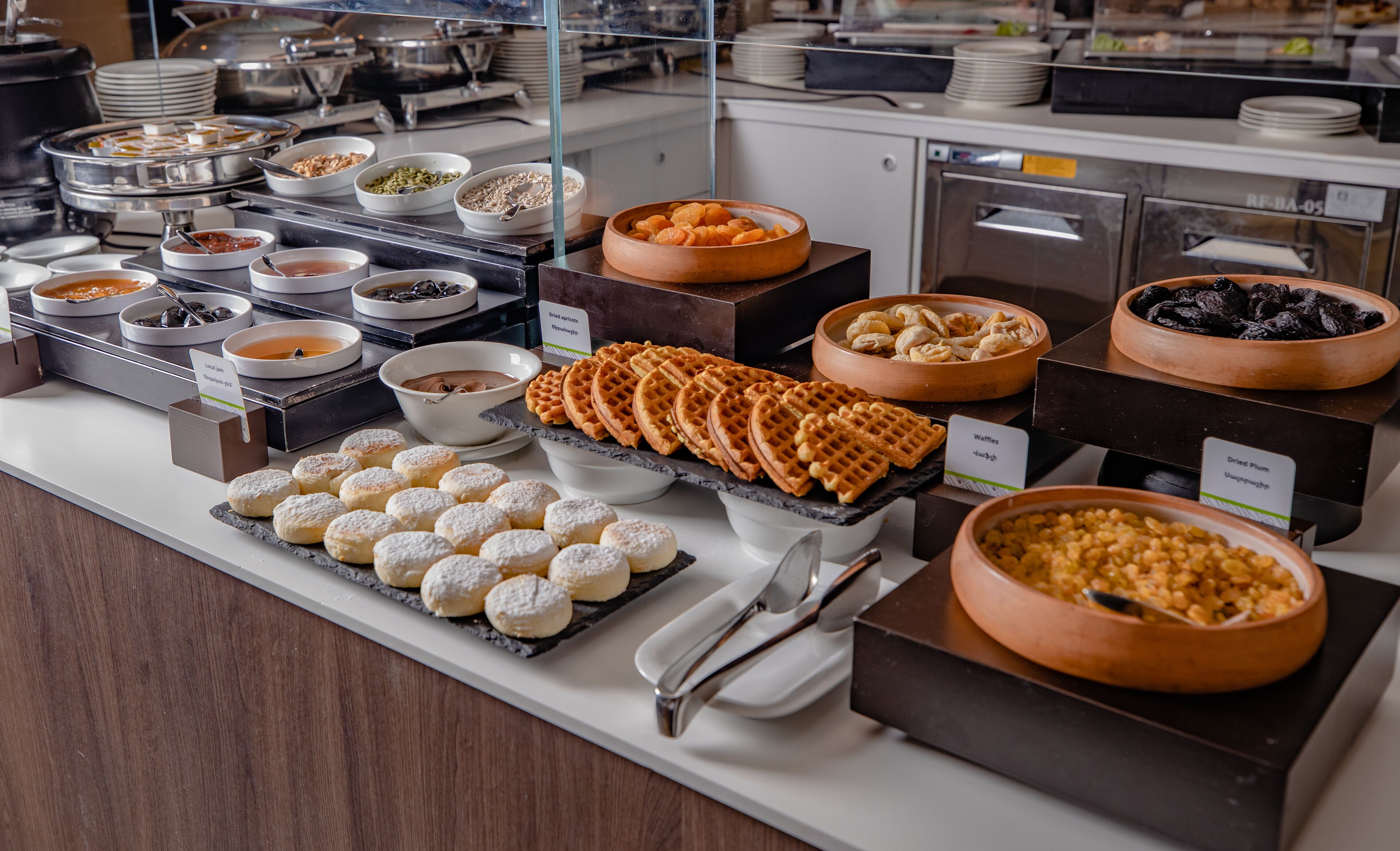 A buffet with various food items including waffles, pastries, and bowls of different dishes.