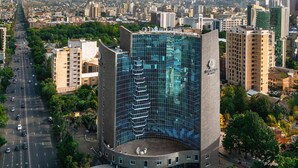 Un bâtiment moderne à la façade en verre, entouré d’un parking et d’espaces verts.
