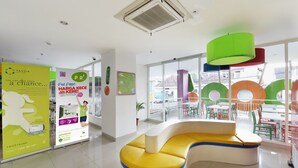 A modern interior with a curved yellow and white seating area, large windows, and colorful outdoor furniture visible through the glass.