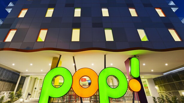 A hotel facade with a modern design, featuring a prominent 'pop!' sign at the entrance.