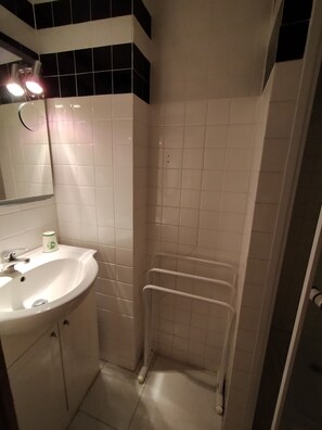 Une salle de bain équipée d’un lavabo, d’un miroir et d’une douche avec une barre d’appui.