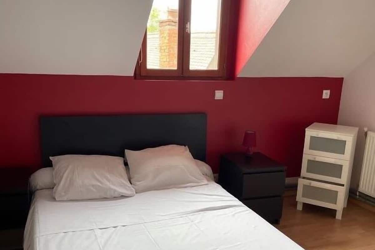 A bedroom with a bed, nightstands, a dresser, and a window.