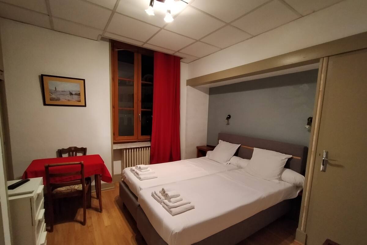 A bedroom with a bed, a table, and a chair.