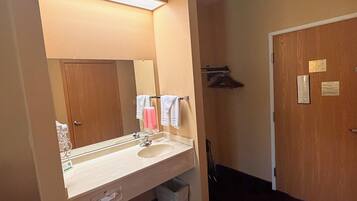 A hotel bathroom with a sink, mirror, and towel rack.