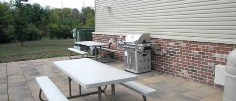 An outdoor patio with picnic tables and a grill.