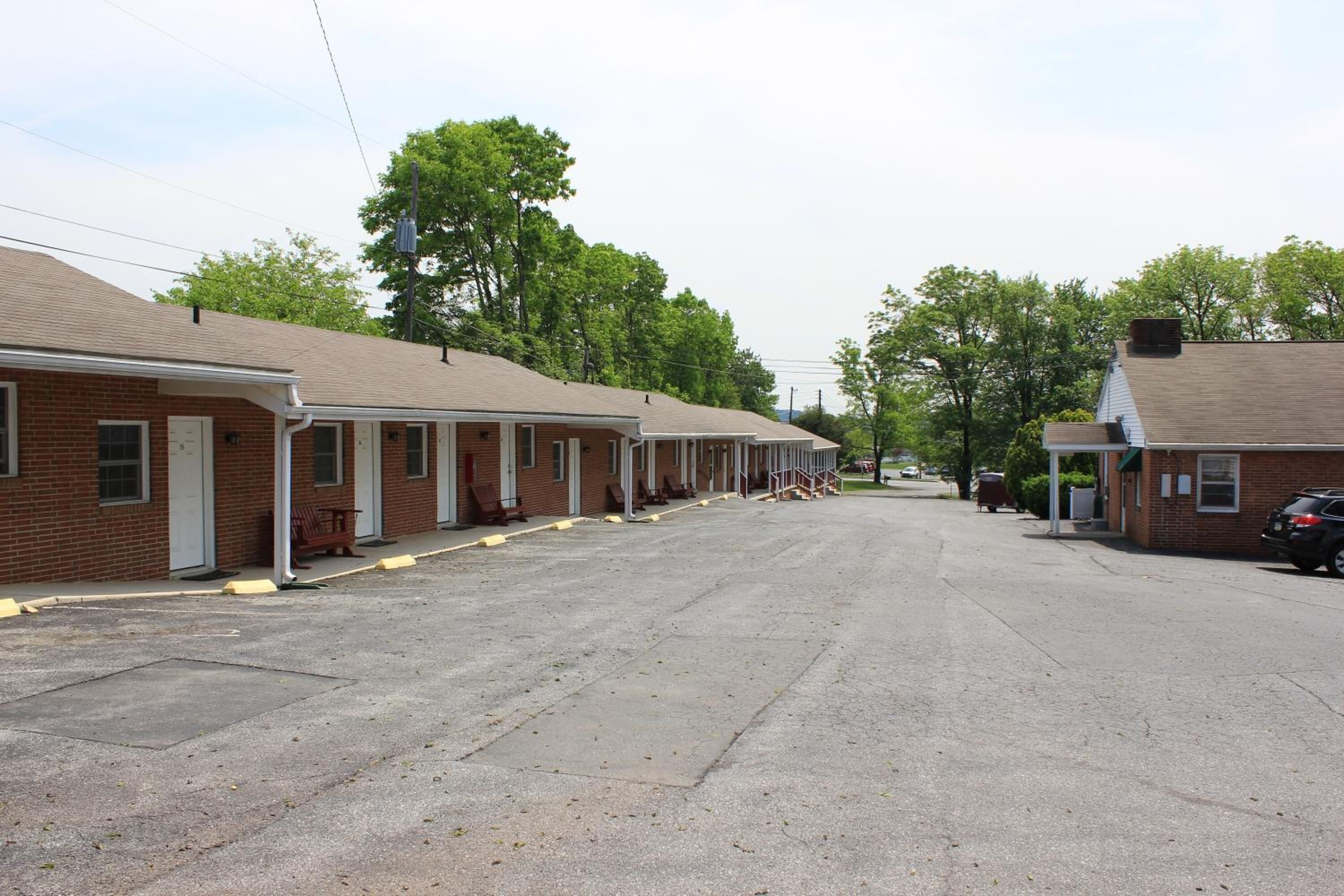A row of single-story brick motel buildings with individual driveways and a parking lot.
