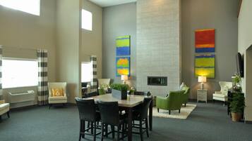 A hotel lobby with a dining area, seating, a fireplace, and artwork on the walls.