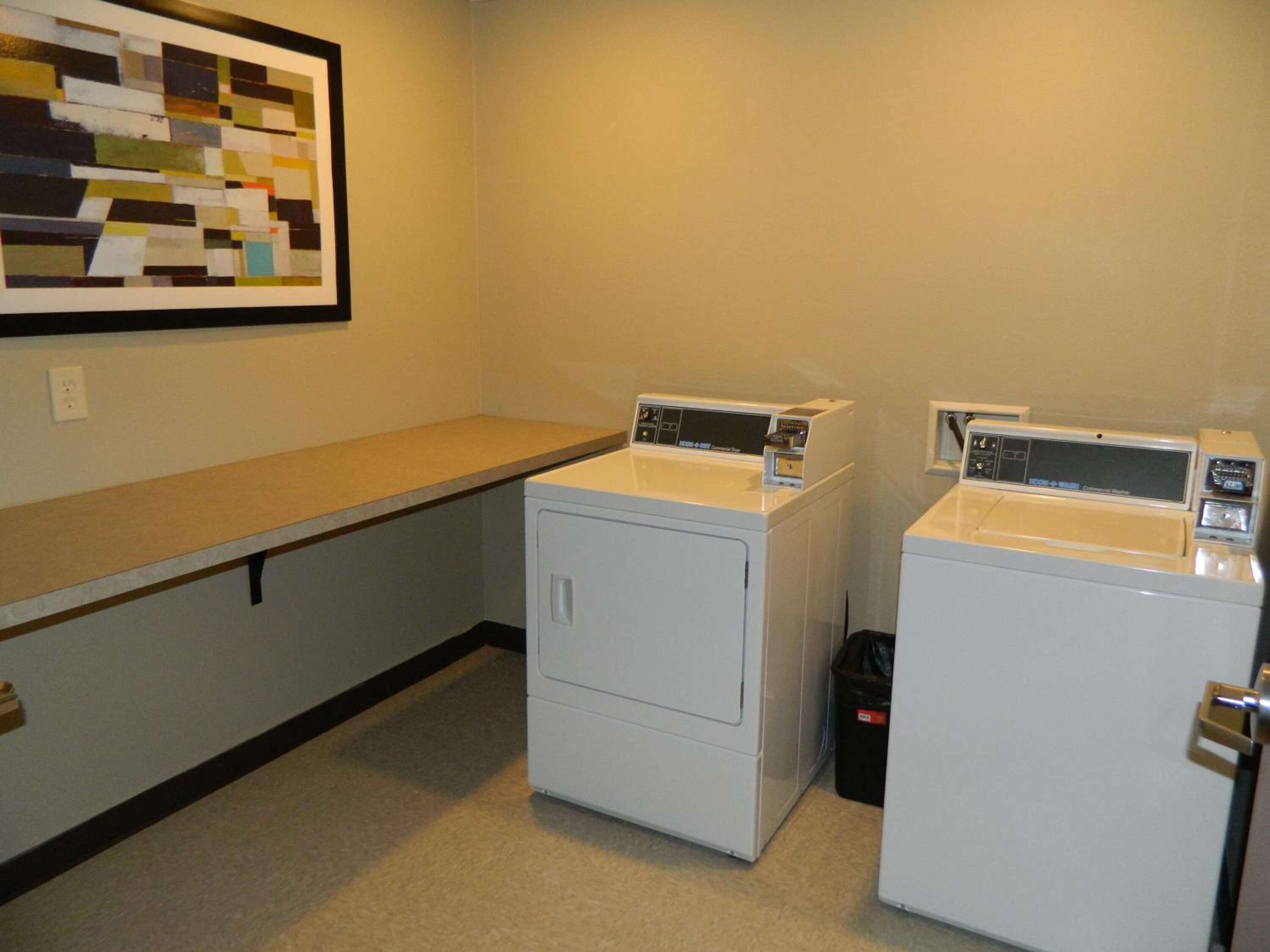 A laundry room with two white washing machines and a beige countertop.