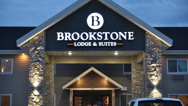 A building with a sign reading "BROOKSTONE LODGE & SUITES" and a stone facade. - Brookstone Lodge & Suites (Algona)