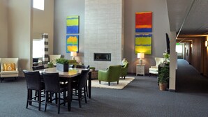 A modern hotel lobby with a dining area, seating, a fireplace, and artwork on the walls. - Brookstone Lodge & Suites (Algona)