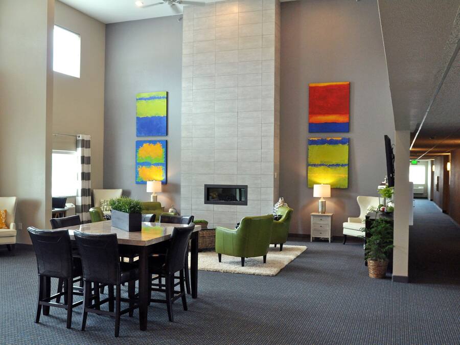 A modern hotel lobby with a dining area, seating, a fireplace, and artwork on the walls.