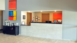 A reception area with a black counter, a wooden cabinet with various items, and two framed certificates on the wall. - Brookstone Lodge & Suites (Algona)
