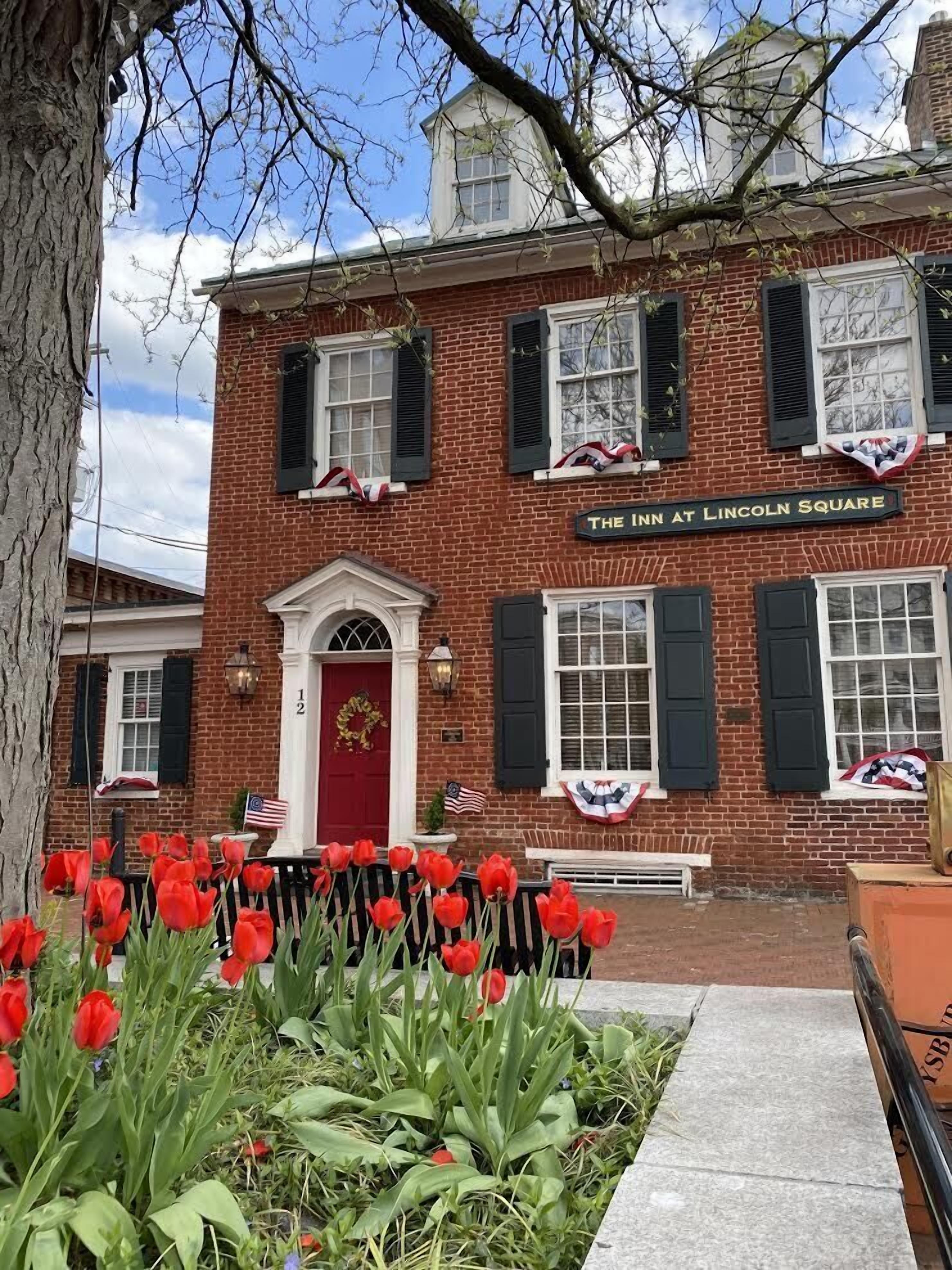 A brick building with a red door and windows with shutters, labeled "The Inn at Lincoln Square".