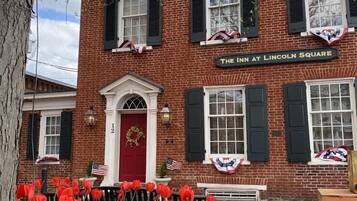 A brick building with a red door and windows with shutters, labeled "The Inn at Lincoln Square".