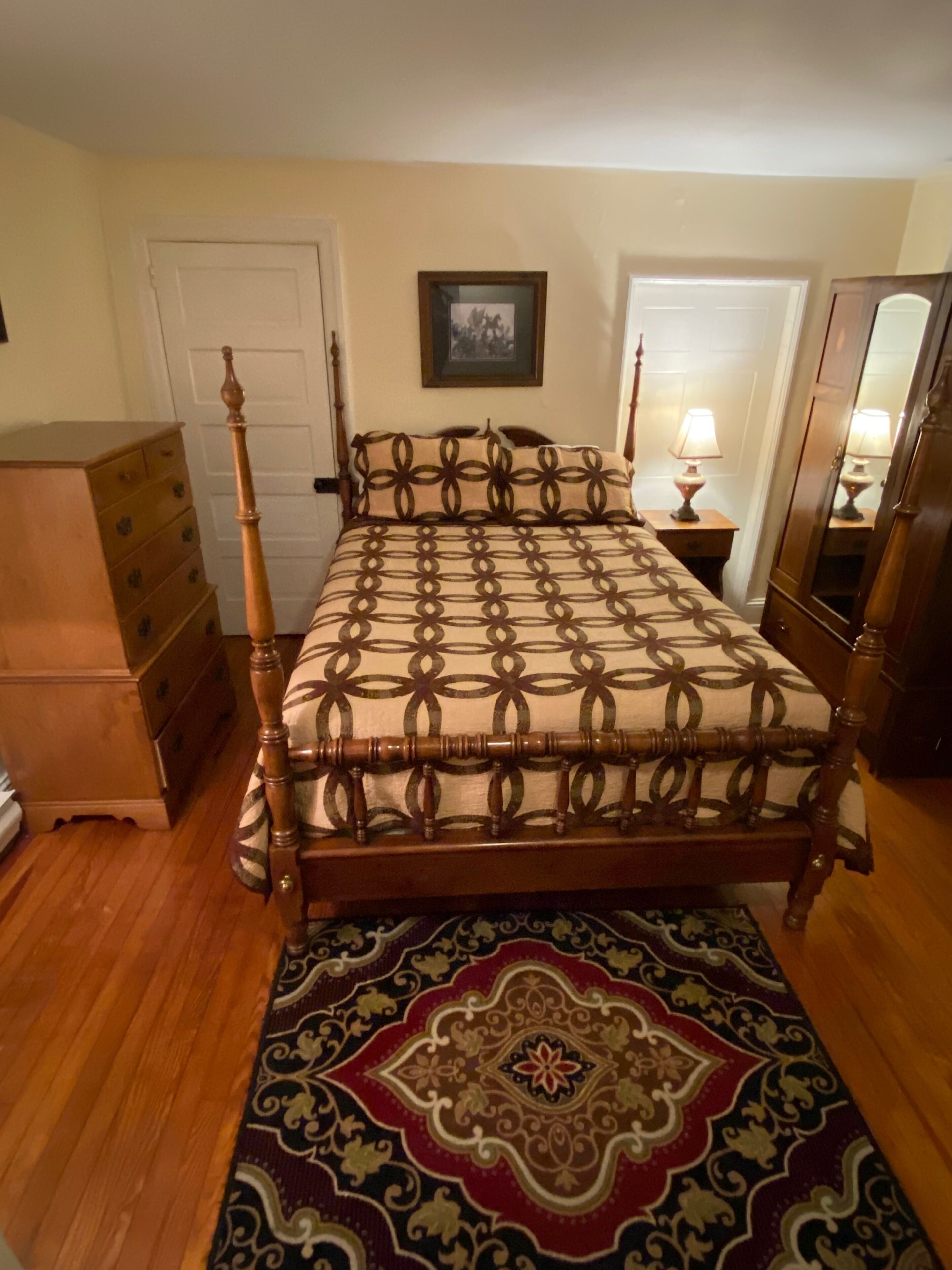 Une chambre à coucher avec un lit à baldaquin en bois, une commode, une table de chevet avec une lampe et un miroir.