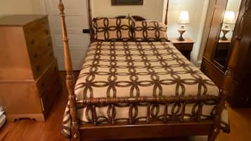Une chambre à coucher avec un lit à baldaquin en bois, une commode, une table de chevet avec une lampe et un miroir.