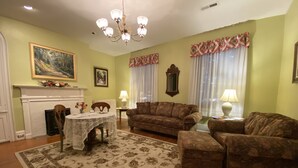 Una sala de estar con chimenea, un sofá, un tapete estampado y un candelabro.