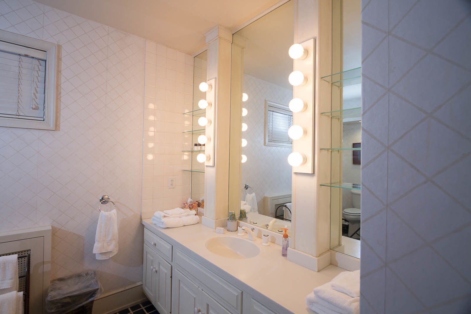 Un baño con un espejo grande, tocador y varias luces.
