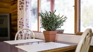 Una mesa de madera con dos sillas blancas, una planta en maceta y una ventana con cortina.