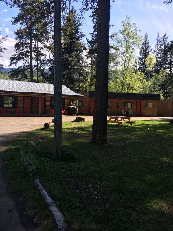 A lodge with a covered outdoor seating area, picnic tables, and a view of surrounding trees. - Overlook Inn & Cabins (Clearwater)