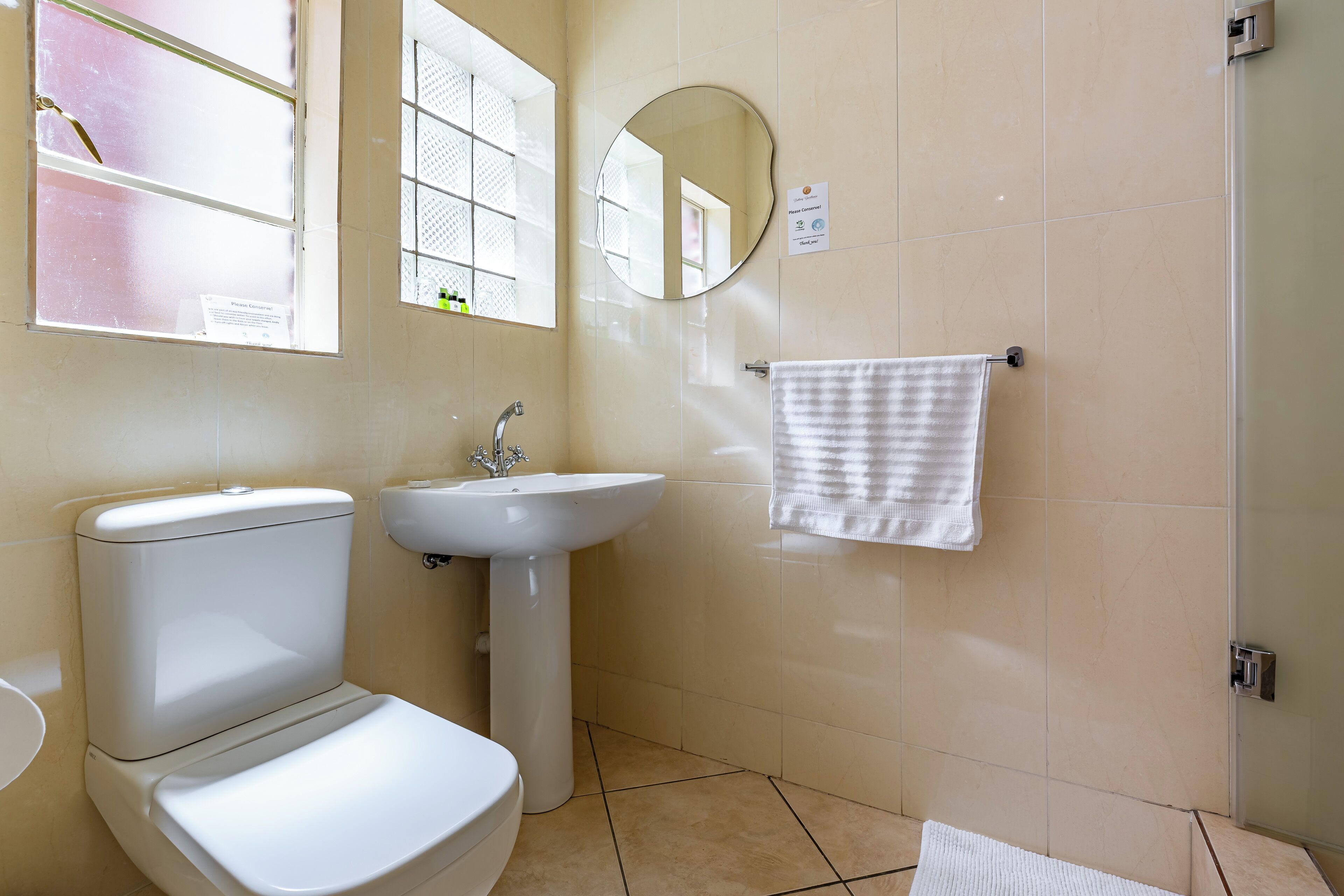 A bathroom with a toilet, sink, mirror, and towel rack.