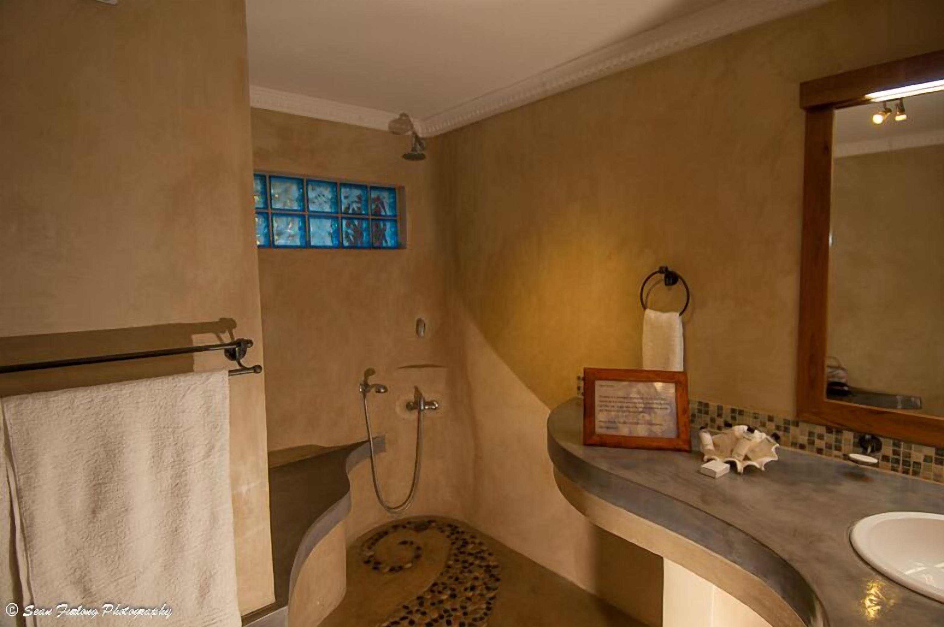 Ein Badezimmer mit Dusche, Waschbecken und Spiegel.