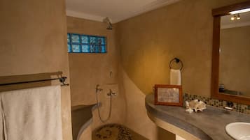 Ein Badezimmer mit Dusche, Waschbecken und Spiegel.